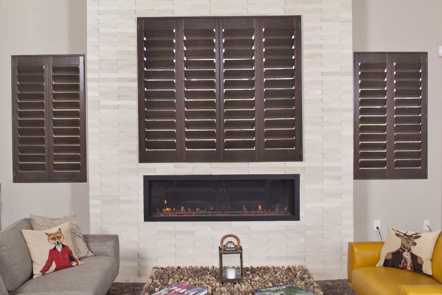 Wood Ovation shutters bring class and warmth to home decor. Brown wood shutters in an off-white living room
